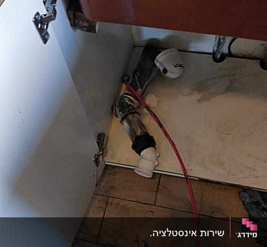 צנרת מתחת לכיור במטבח עם כלים